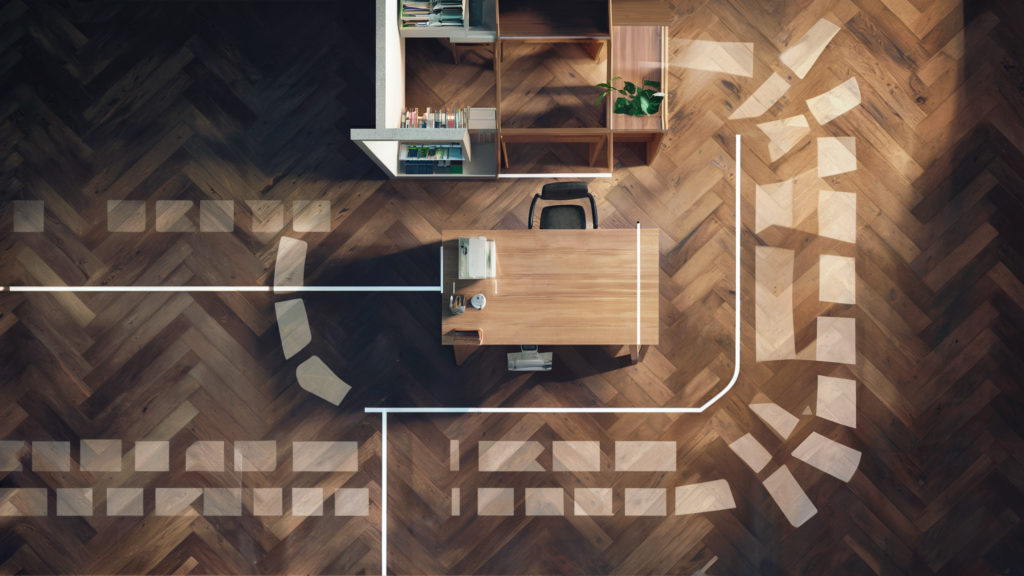 An overhead view of the best desk placement in a modern office, highlighting a wooden desk with a lamp, books, and plant on a parquet floor with dynamic sunlight.